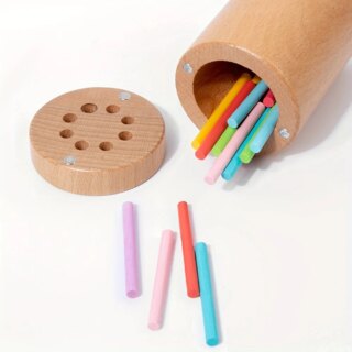 Jeu de pailles à glisser dans des trous : motricité fine Montesssori, boîte cylindrique en bois et pailles en bois colorées.