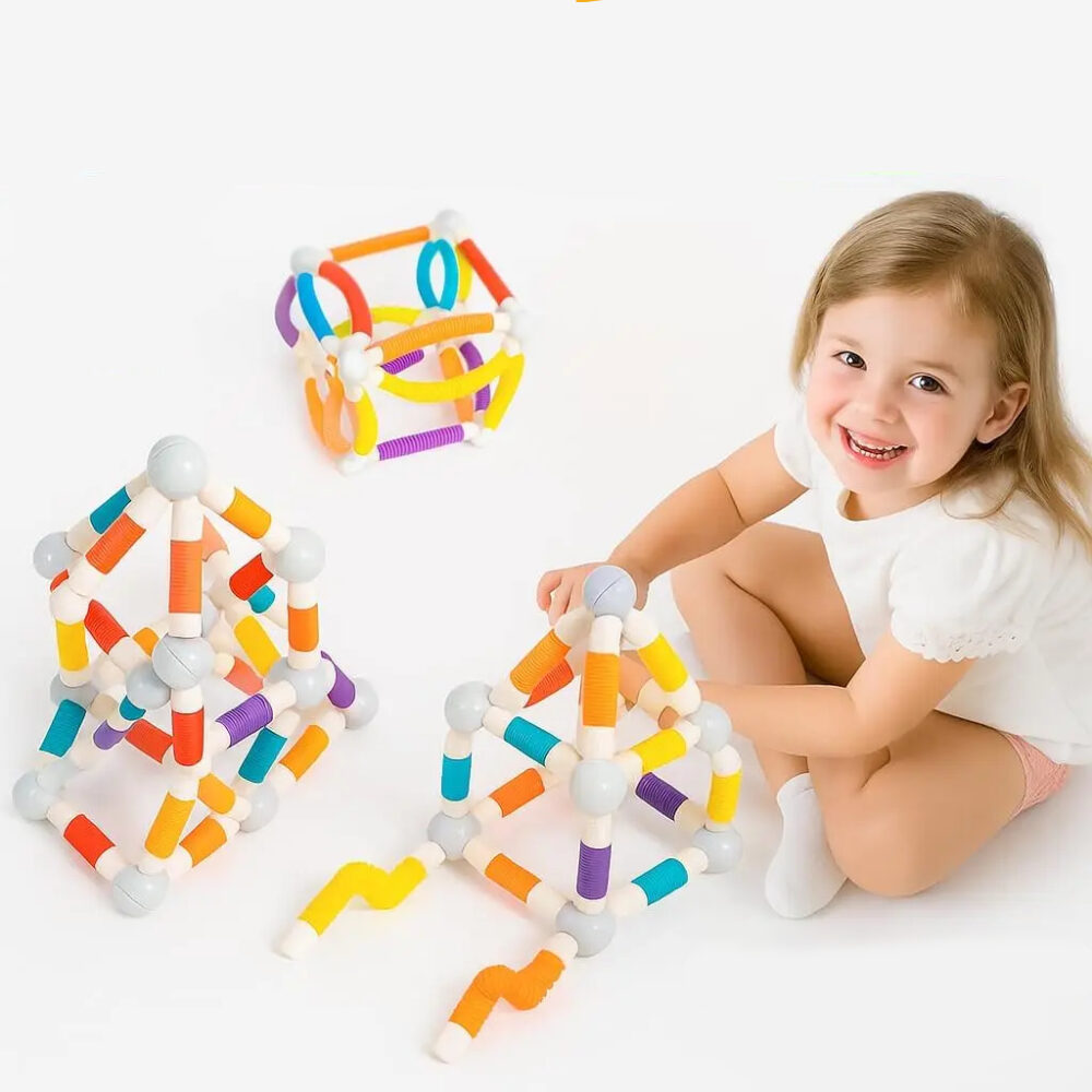 Petite fille qui joue à un jeu de construction magnétique coloré par terre