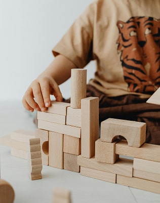 Mains d'enfant jouant avec des jouet en bois pour faire un château