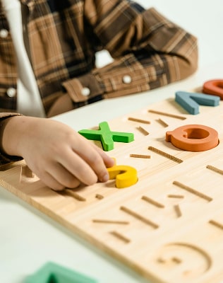 Mains d'enfant jouant avec un plateau de jeux avec des figure géométrique